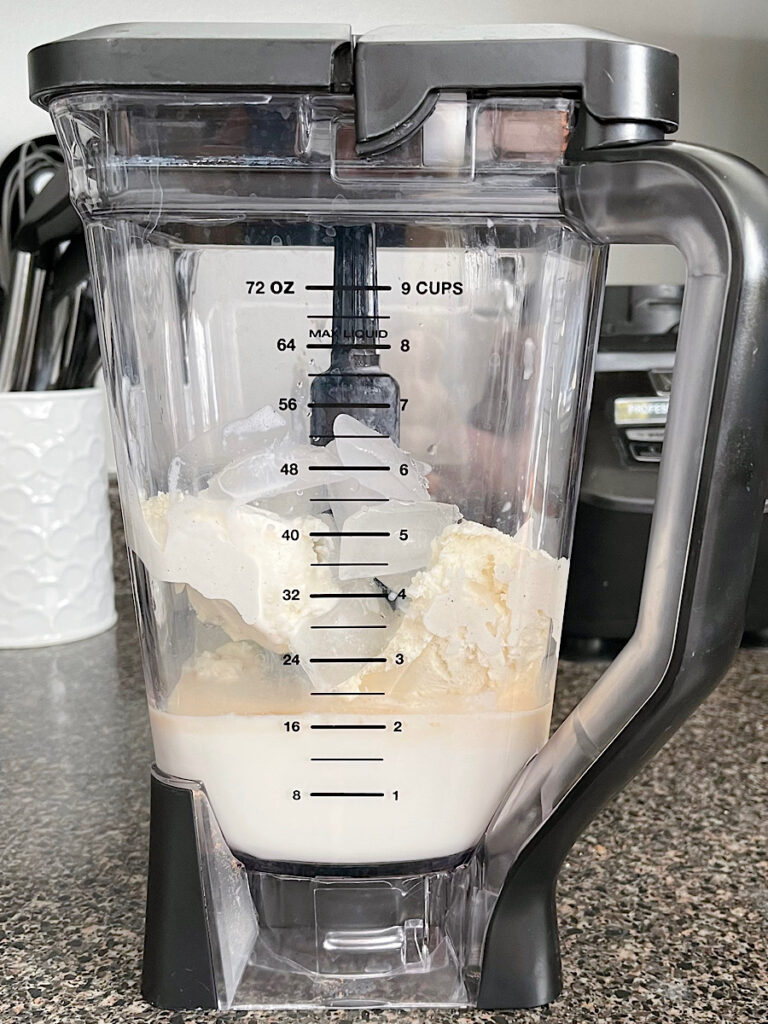 Ice, ice cream, milk, syrup, and vanilla in a blender.
