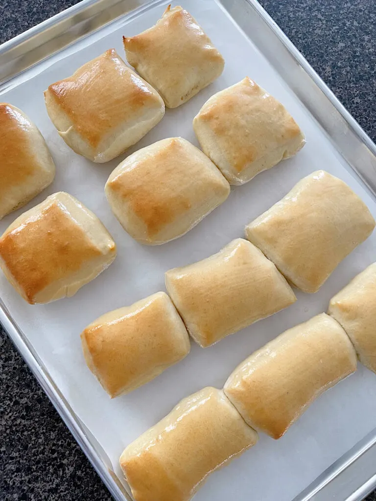 Freshly baked Texas Roadhouse rolls on a baking sheet.