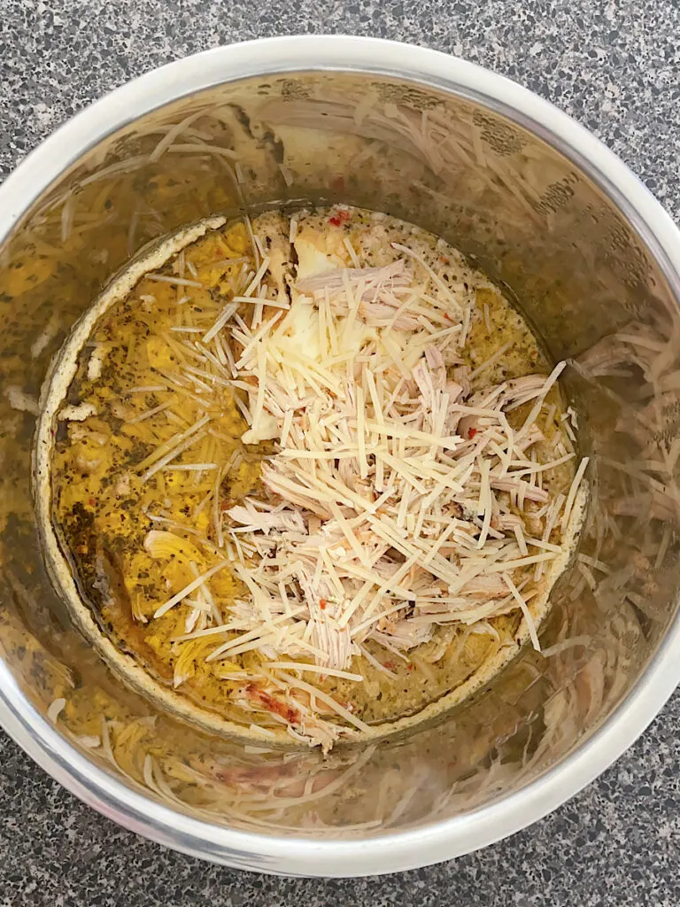 Shredded chicken and garlic parmesan sauce in a an Instant Pot.