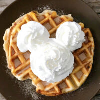 An overnight yeast waffle that tastes like a funnel cake topped with a Mickey Mouse-shaped whipped cream.