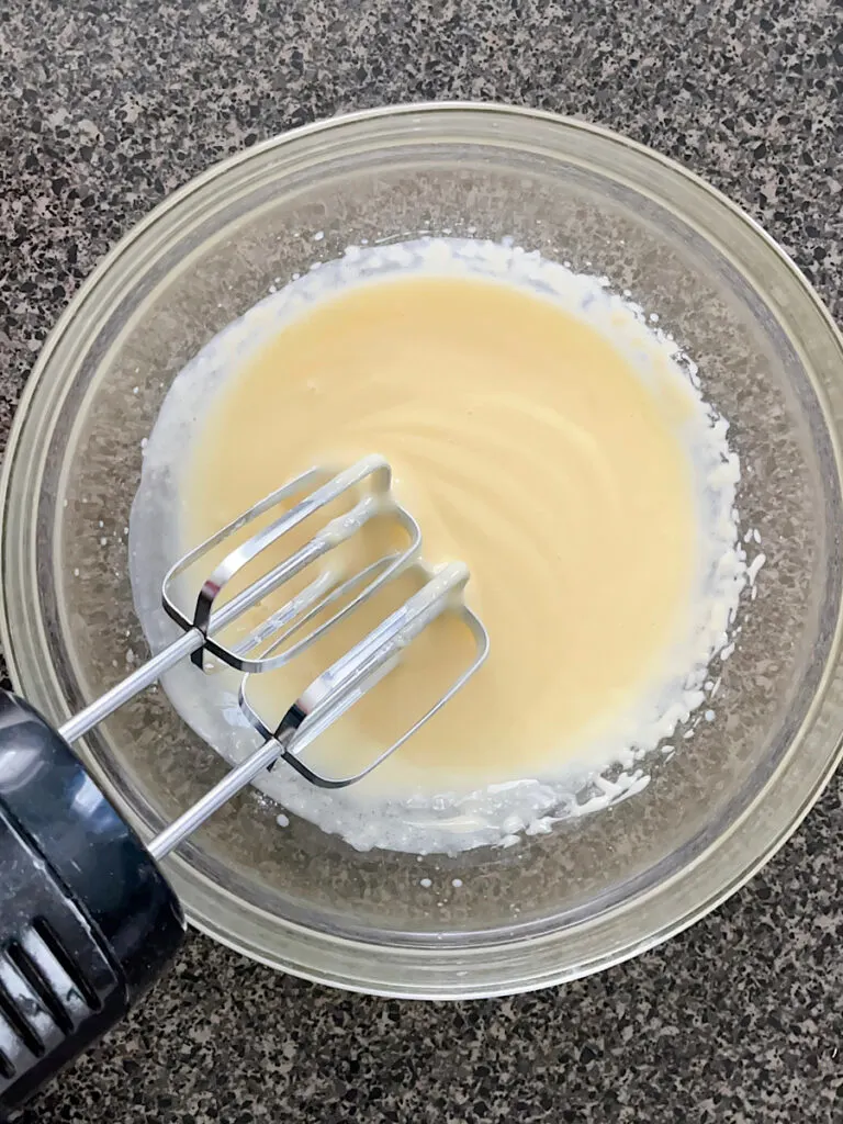 A bowl of instant pudding and an electric mixer.