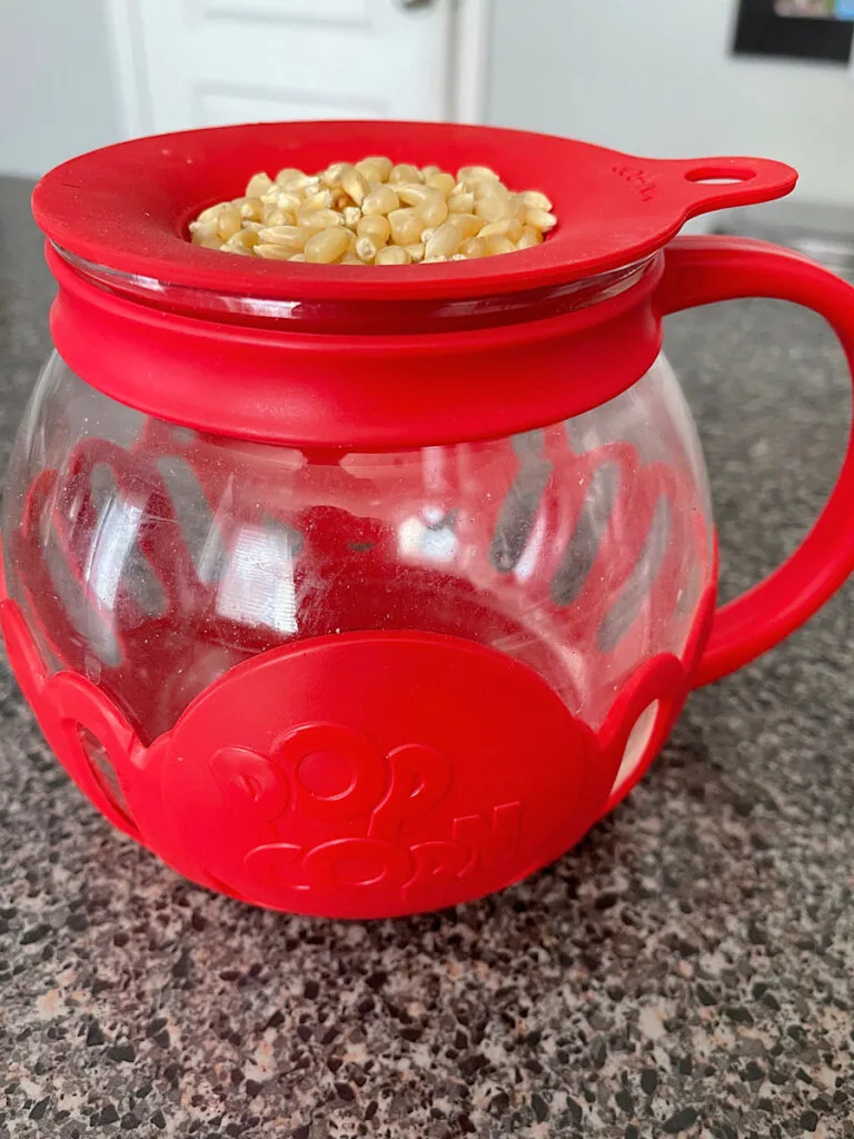Popcorn kernels in a red microwave popcorn popper.