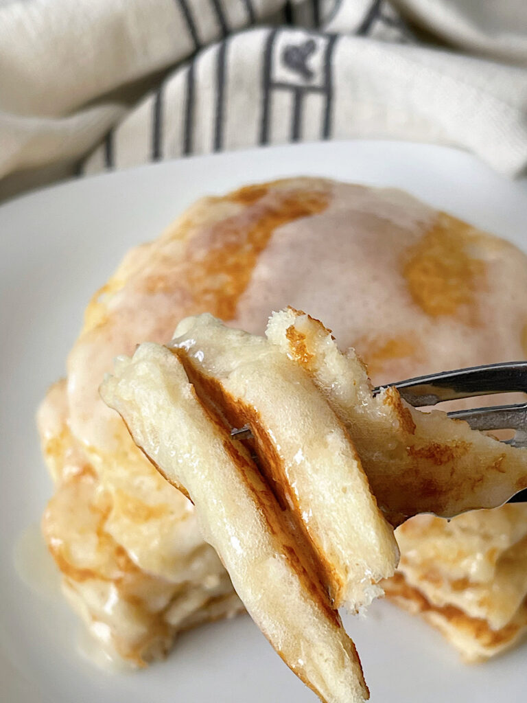 A stack of buttermilk pancakes made with Bisquick topped with butter and buttermilk syrup.