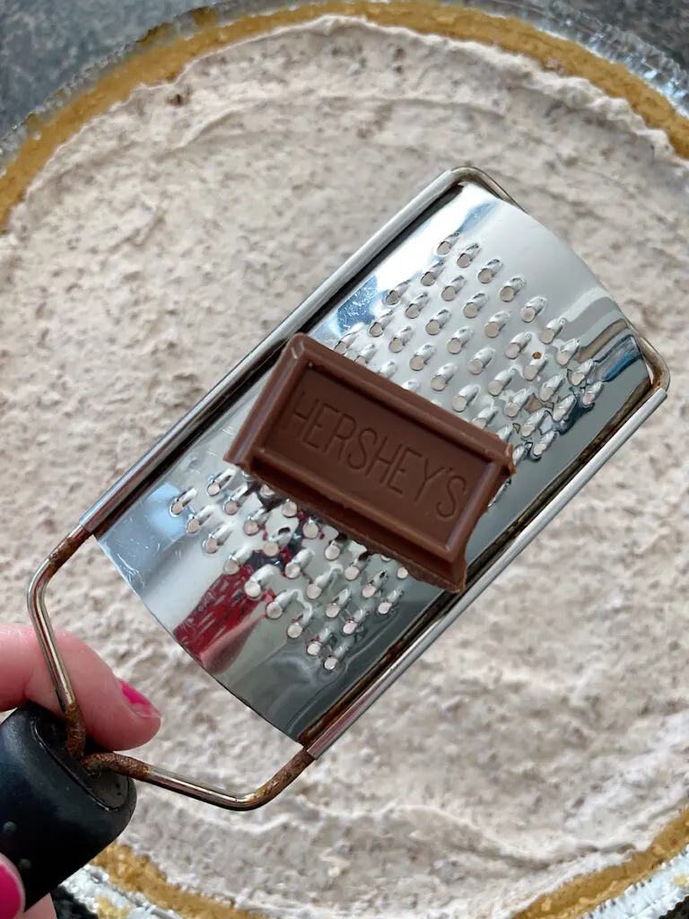 Chocolate and a small cheese grater with a chocolate Cool Whip pie.