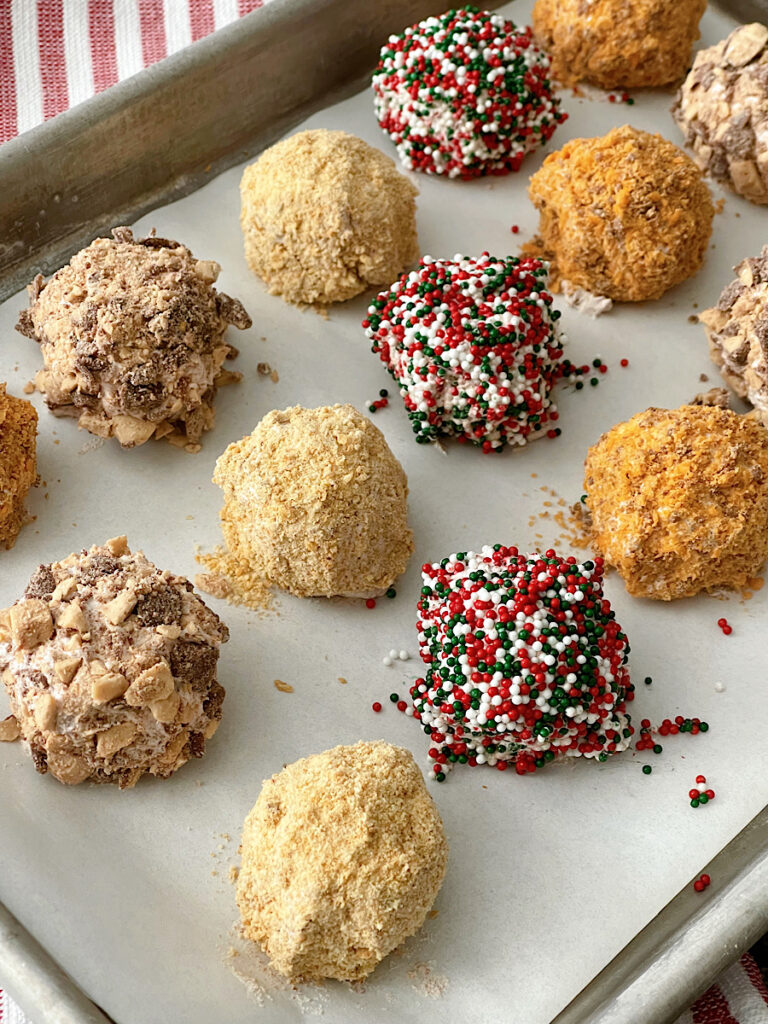 Cool Whip candy truffles with different toppings on a parchment paper lined baking sheet.