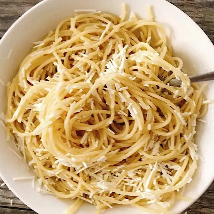 A bowl of browned butter spaghetti topped with Mizithra cheese.