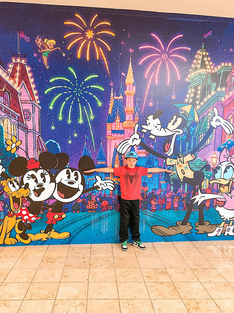 A boy in front of a Disney mural at Orlando International Airport.
