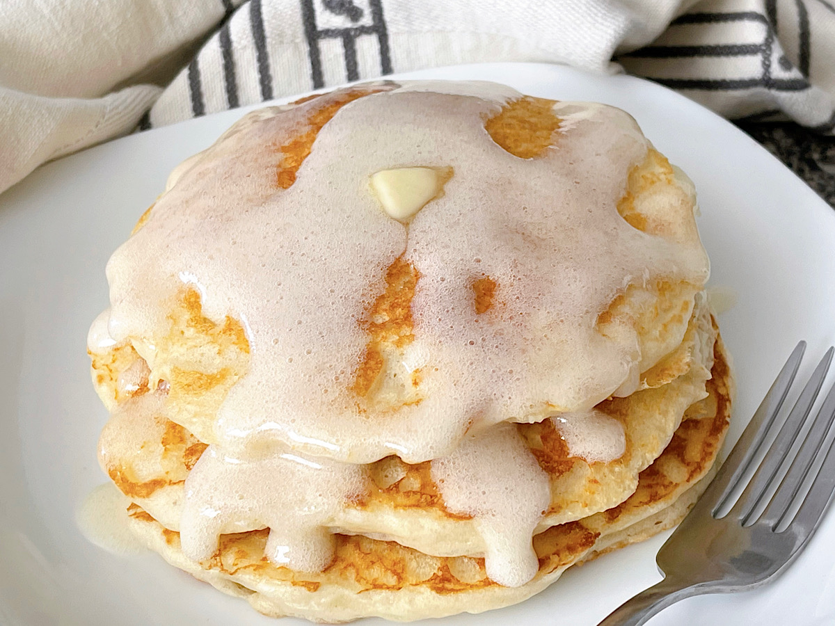 A stack of buttermilk pancakes made with Bisquick topped with butter and buttermilk syrup.