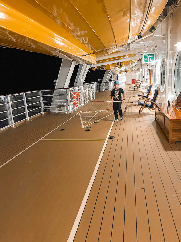 A child playing shuffleboard on the Disney Wish.