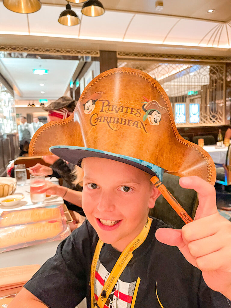 A boy wearing a Pirates of the Caribbean hat on the Disney Wish.