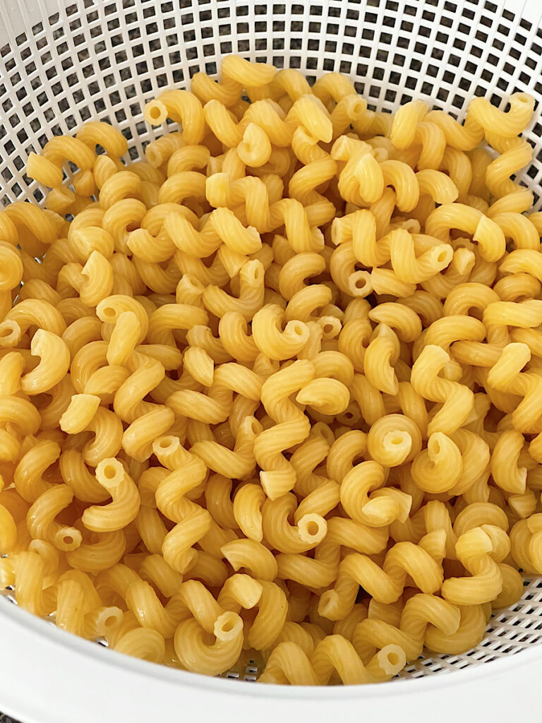 Cellentani pasta in a strainer to make skillet macaroni and cheese.