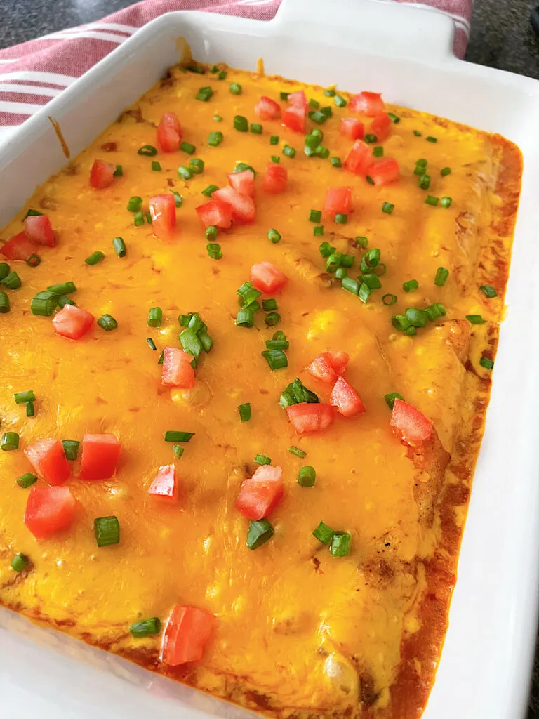 A pan of lazy enchiladas made with taquitos, enchilada sauce, and cheese.
