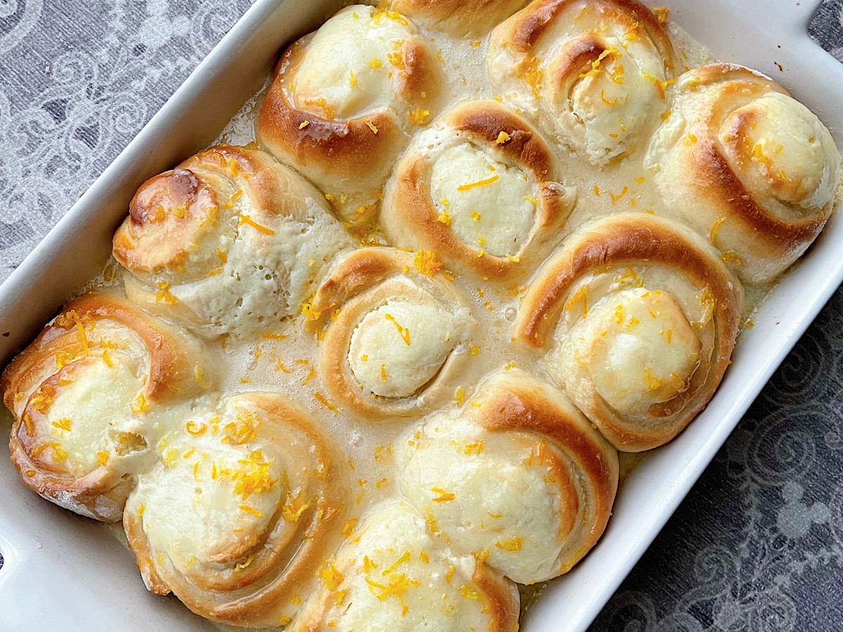 Homemade Orange Rolls with orange glaze in a baking dish.