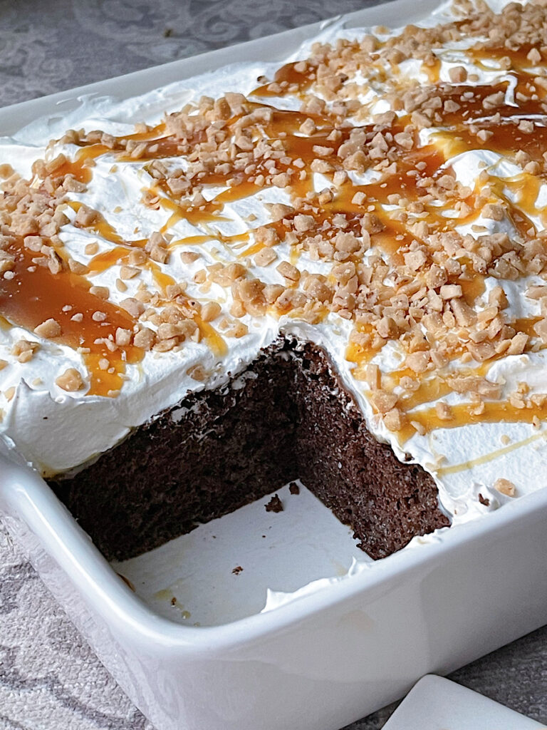 A chocolate poke cake with one slice missing.