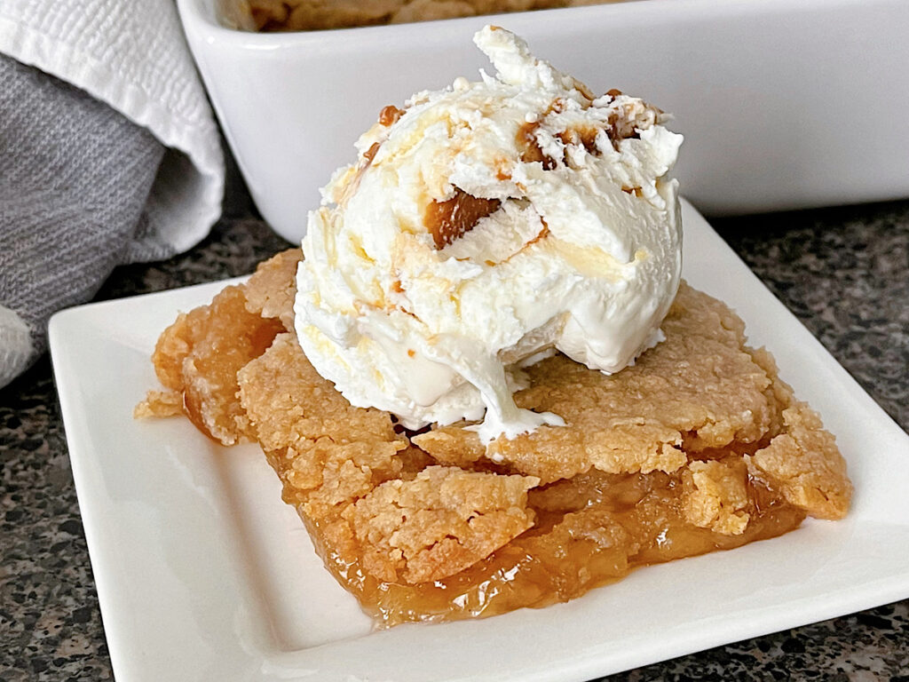 Apple Crisp made with apple pie filling on a white plate topped with a scoop of ice cream.