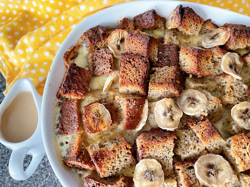 A dish of banana bread pudding with a yellow towel.