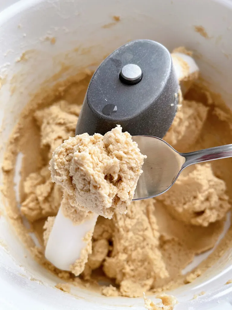 Cookie butter cookie dough on a spoon over a bowl of cookie dough.