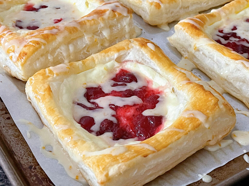 Cranberry cream cheese Danishes made with Puff Pastry dough and drizzled with orange glaze.