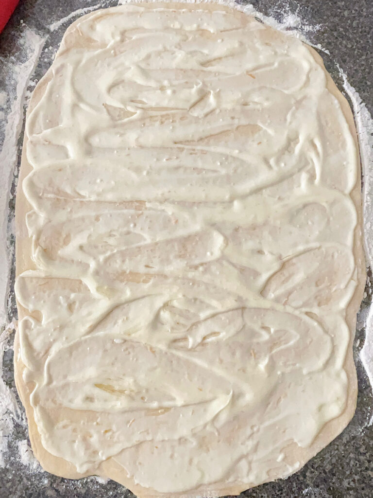 Orange cream cheese filling spread over sweet roll dough.