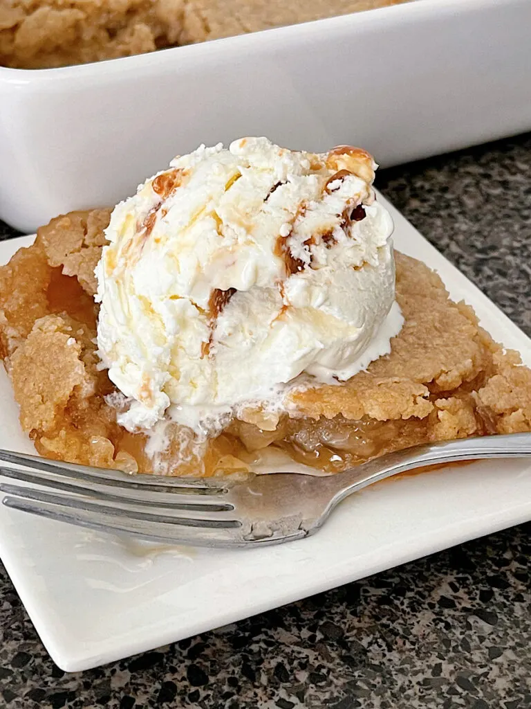 Apple Crisp made with apple pie filling on a white plate topped with a scoop of ice cream.