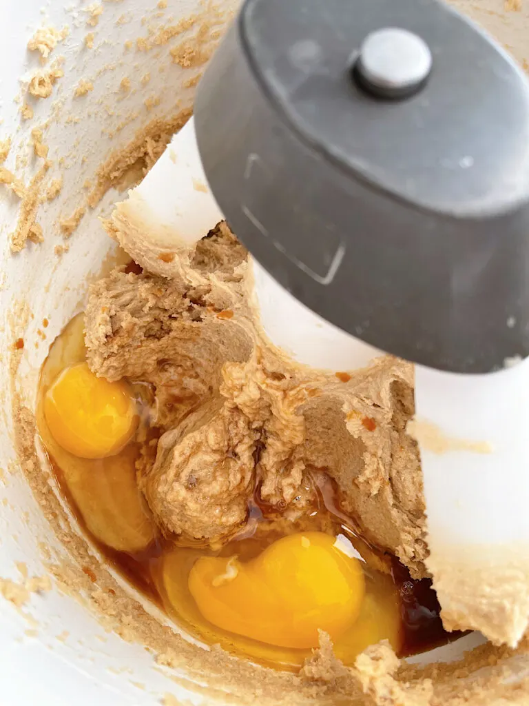 Eggs added to butter and sugar to make cookie dough in a stand mixer.