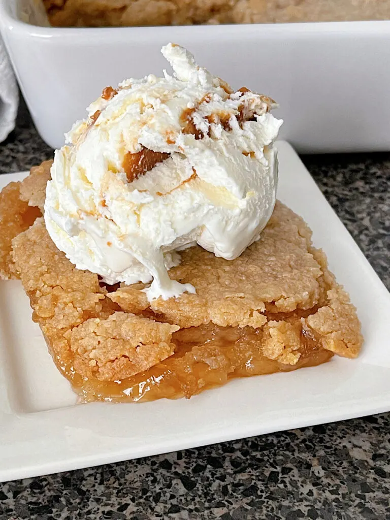 Apple Crisp made with apple pie filling on a white plate topped with a scoop of ice cream.