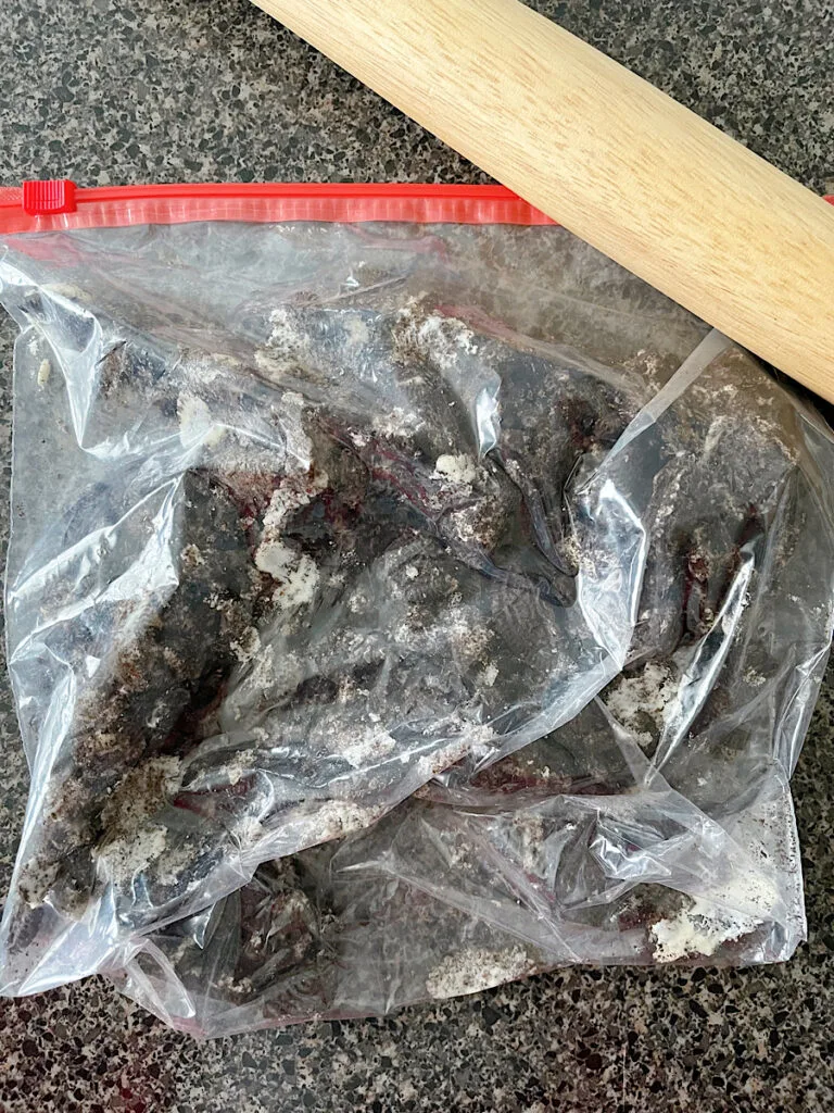 Oreo cookies crushed in a ziplock bag with a rolling pin.