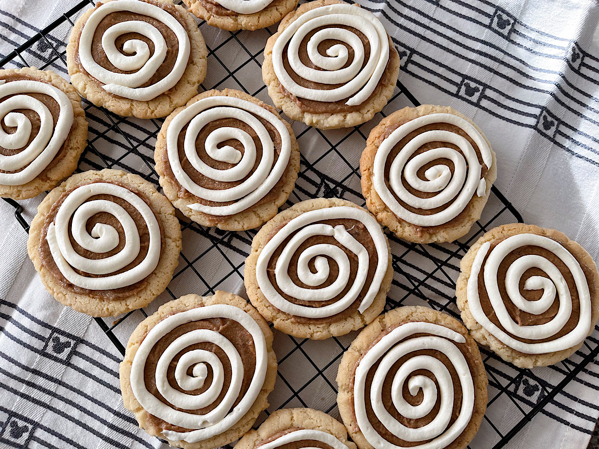 Cinnamon Roll Cookies with cream cheese icing on a cooling rack.
