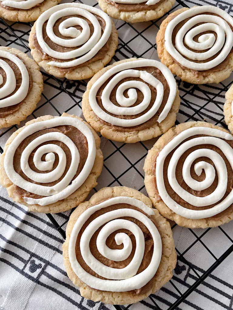 Cinnamon Roll Cookies with cream cheese icing on a cooling rack.