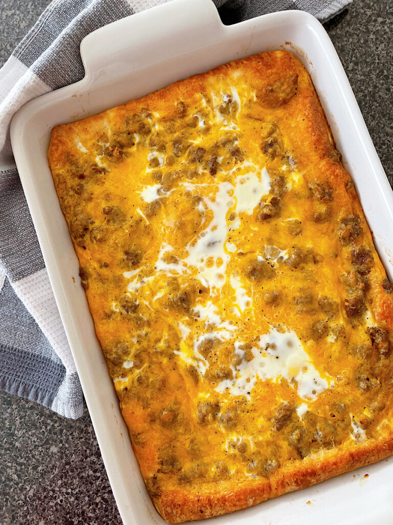 A sausage crescent roll breakfast casserole in a white baking dish.
