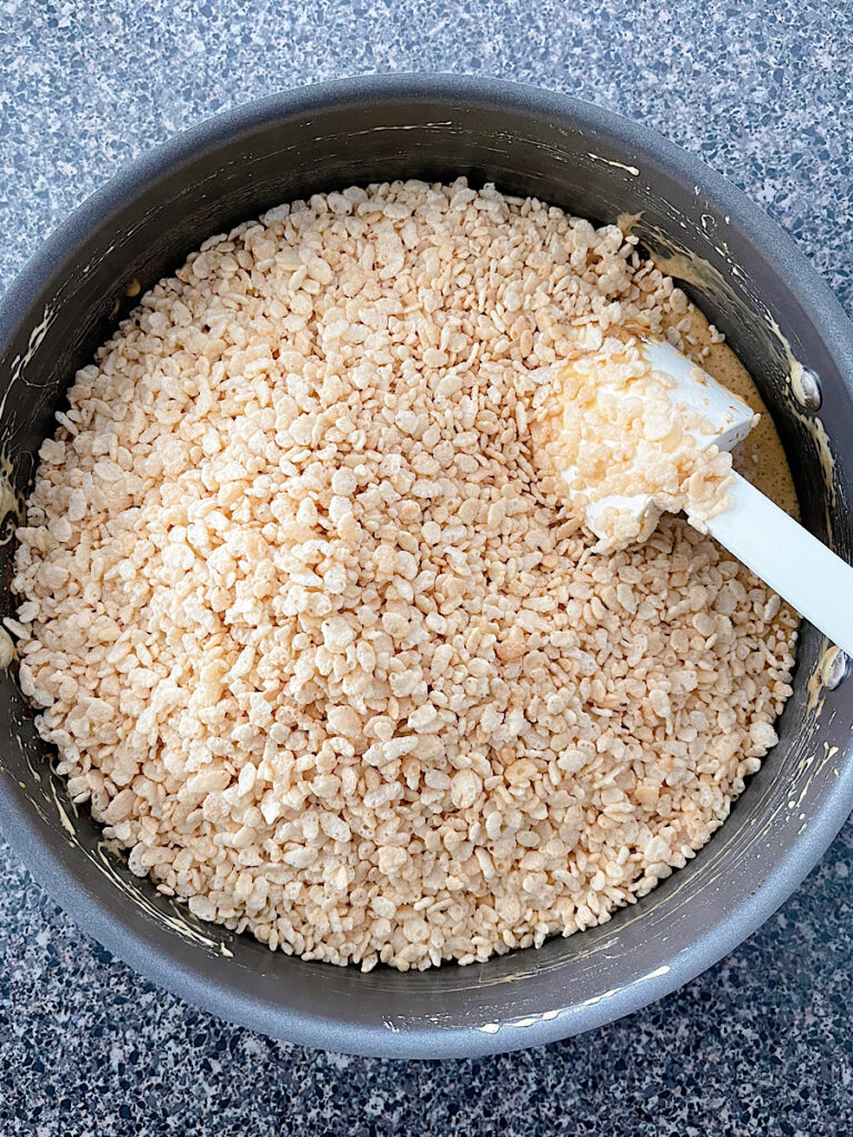 Marshmallow mixture and rice krispies in a pan to make gingerbread rice krispie treats.
