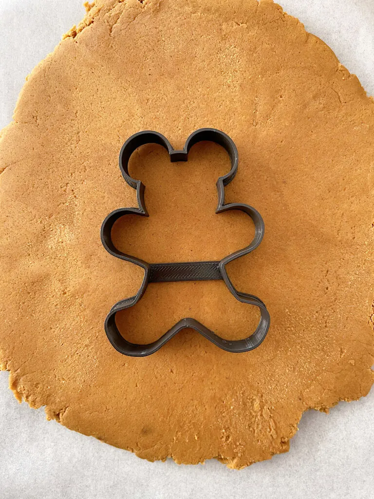 A Mickey mouse gingerbread cookie cutter and gingerbread cookie dough.