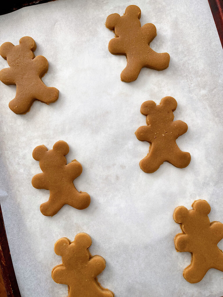 Unbaked Mickey Mouse gingerbread cookies on a parchment paper lined baking sheet.
