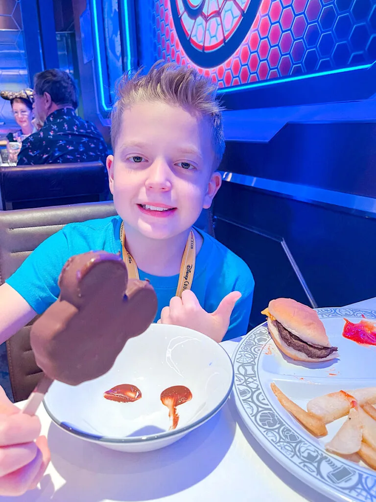 A child eating a Mickey Mouse ice cream bar on a Disney Cruise.