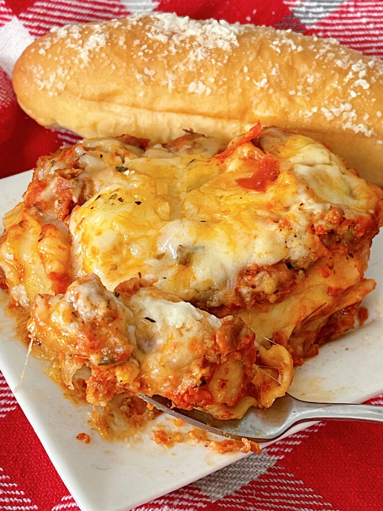 A slice of Bechamel Lasagna with a breadstick.