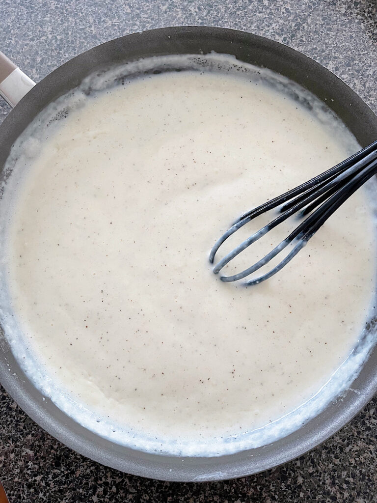 Bechamel sauce in a sauce pan with a whisk.