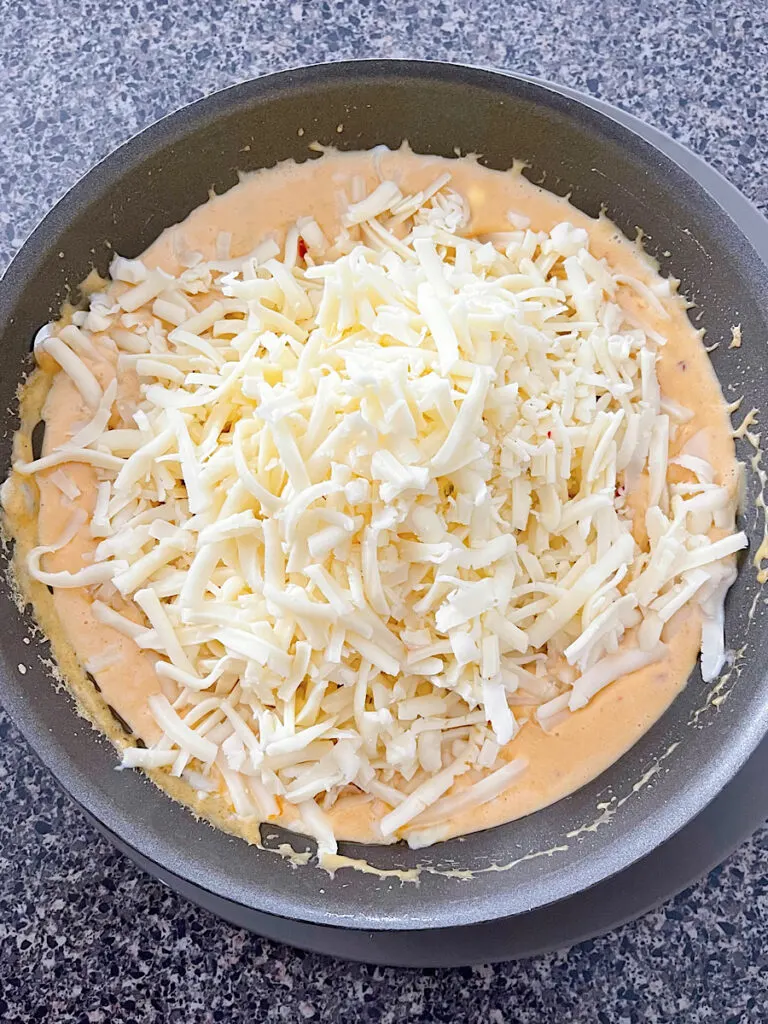 Shredded cheese in a sauce pan to make queso blanco.