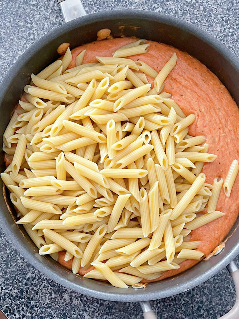 Penne pasta in a skillet with five cheese sauce.