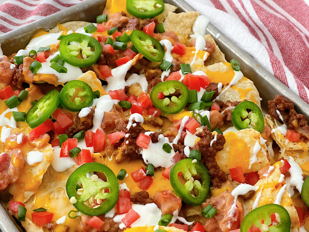 A sheet pan full of nachos with ground beef.