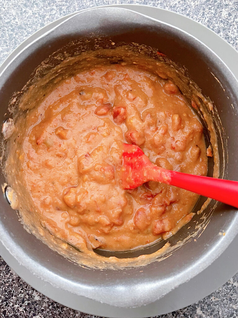 Refried beans mixed with Rotel in a sauce pan.