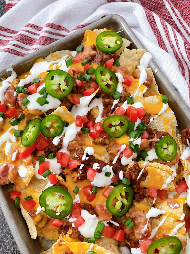 A sheet pan full of nachos with ground beef.