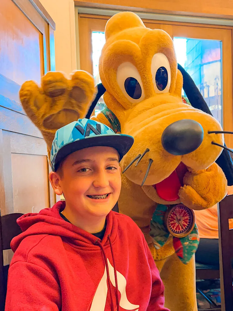 A boy and Pluto at Disney's Storytellers Cafe.
