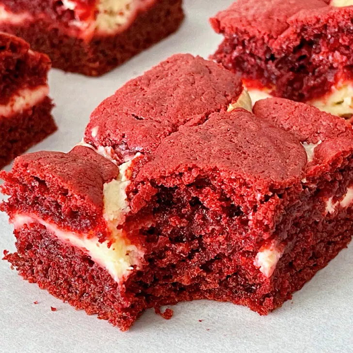 A red velvet brownie swirled with cheesecake with a bite taken out.