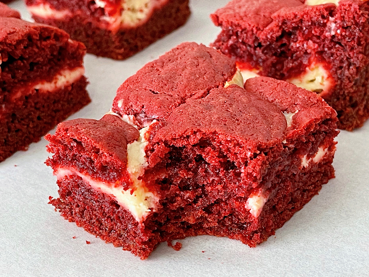 A red velvet brownie swirled with cheesecake with a bite taken out.