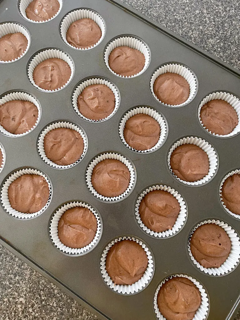 Chocolate cupcake batter in cupcake liners in a pan.