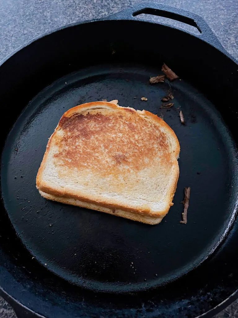 A birria grilled cheese sandwich in a cast iron skillet.