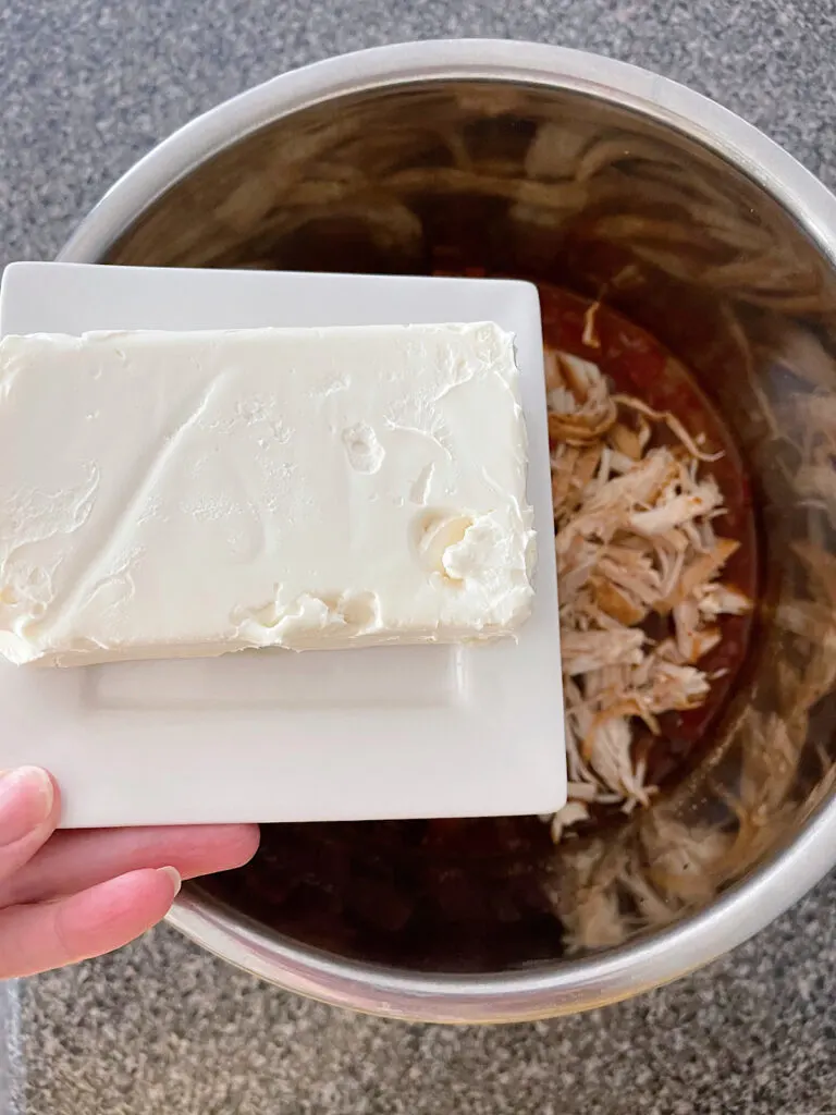 A block of cream cheese over a pot of chili.