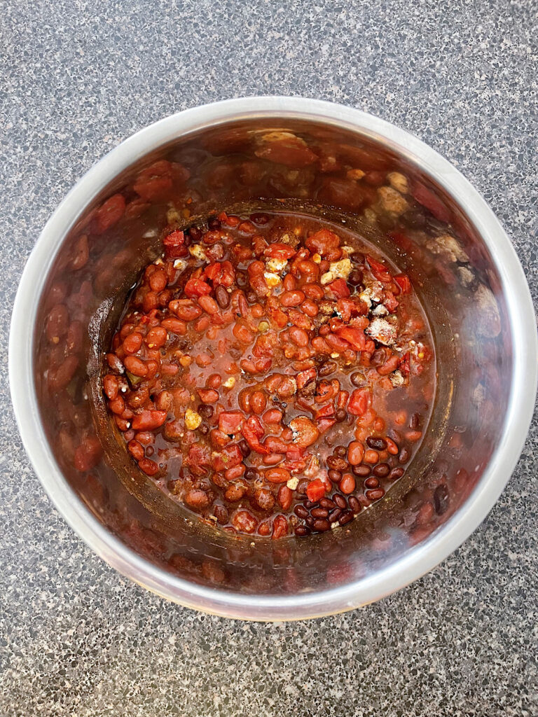 Spices, beans, tomatoes, and chicken in a slow cooker.