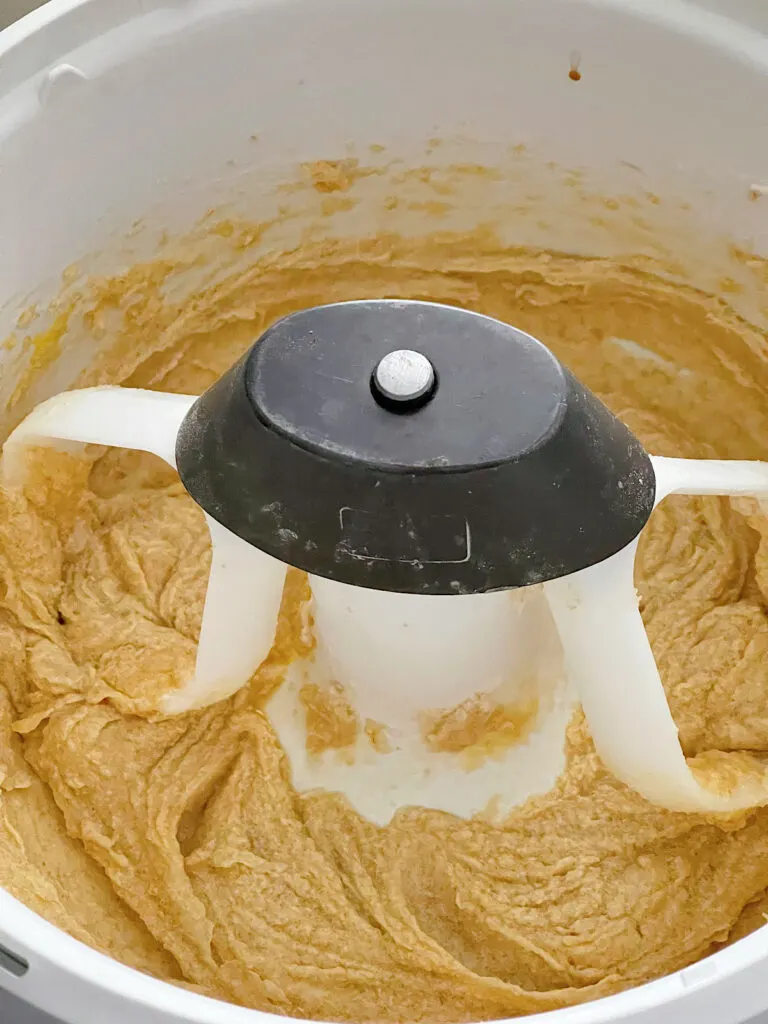 Butter, sugar, vanilla, and eggs mixed together in a bowl of a stand mixer.