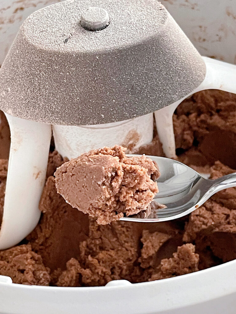 Hot chocolate cookie dough on a spoon over a mixing bowl.